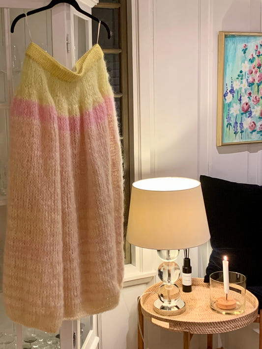 Sunkissed Skirt in yellow, pink and cream mohair hung against a log wall