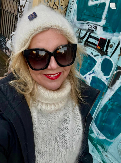 Linn Skåber in an off-white cable hat and sweater